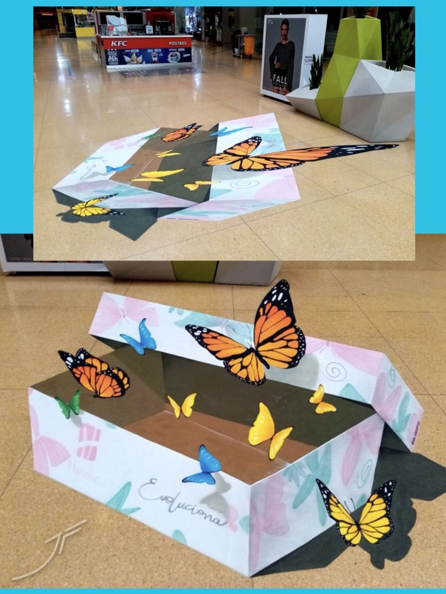 Caja abierta pintada en 3D en el suelo, de la que salen mariposas de colores