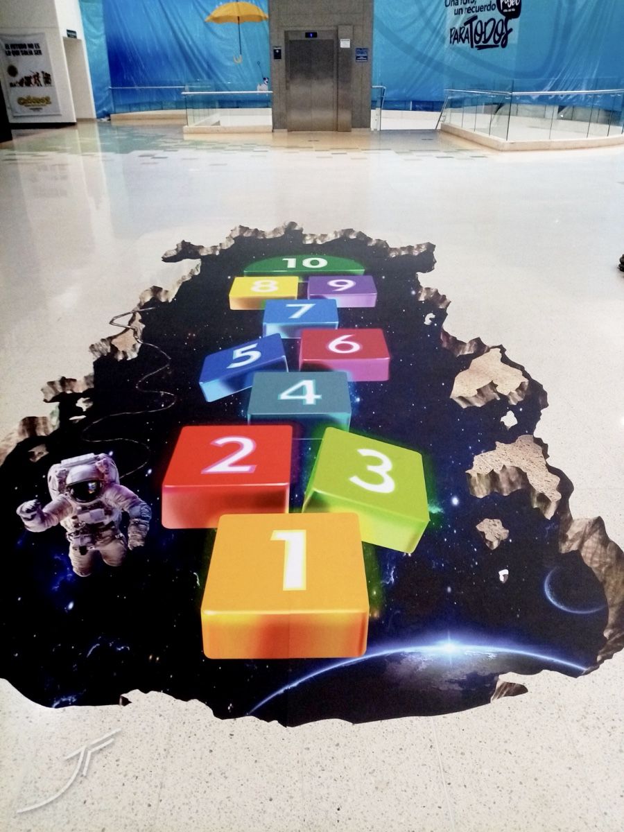 Rayuela con números de colores sobre un agujero en el suelo que muestra el espacio y un astronauta
