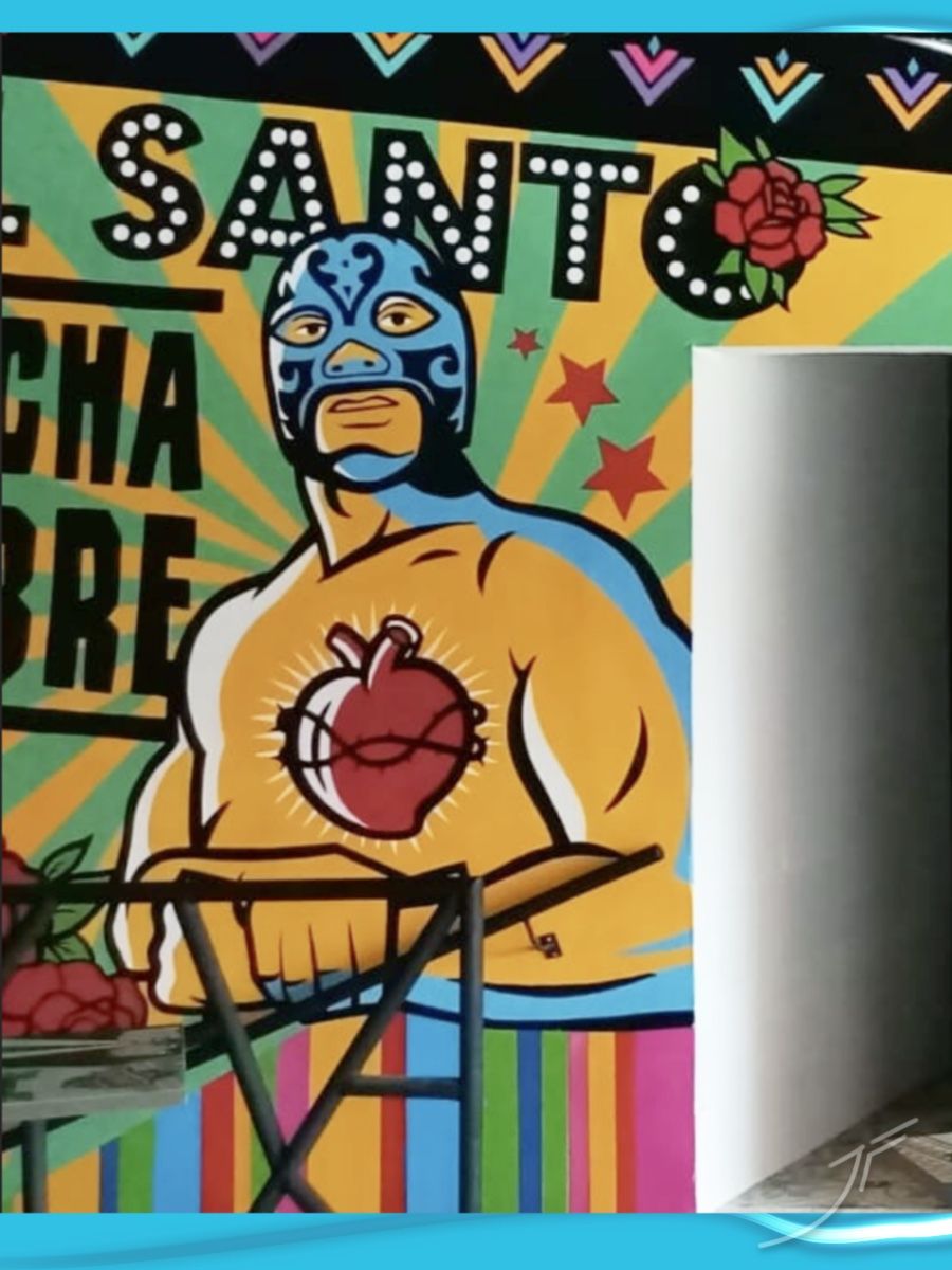 Mural de un luchador enmascarado con un corazón sagrado, letras con luces y colores vivos